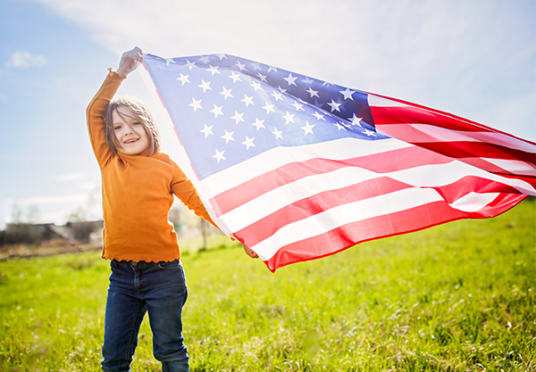 A girl, part of the American Heritage Girls Troop SC1412, holding the American flag and smiling